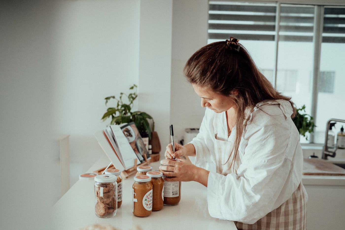 Leila labelling jars of nourishing food in her kitchen